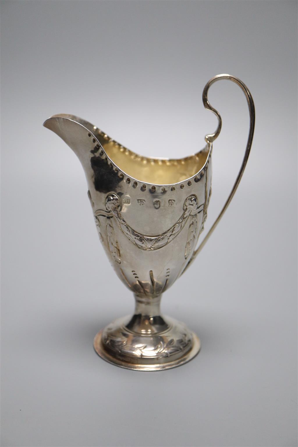 A George III silver helmet shaped cream jug, with later embossed decoration, London, 1773, 14cm, 88 grams (a.f.).